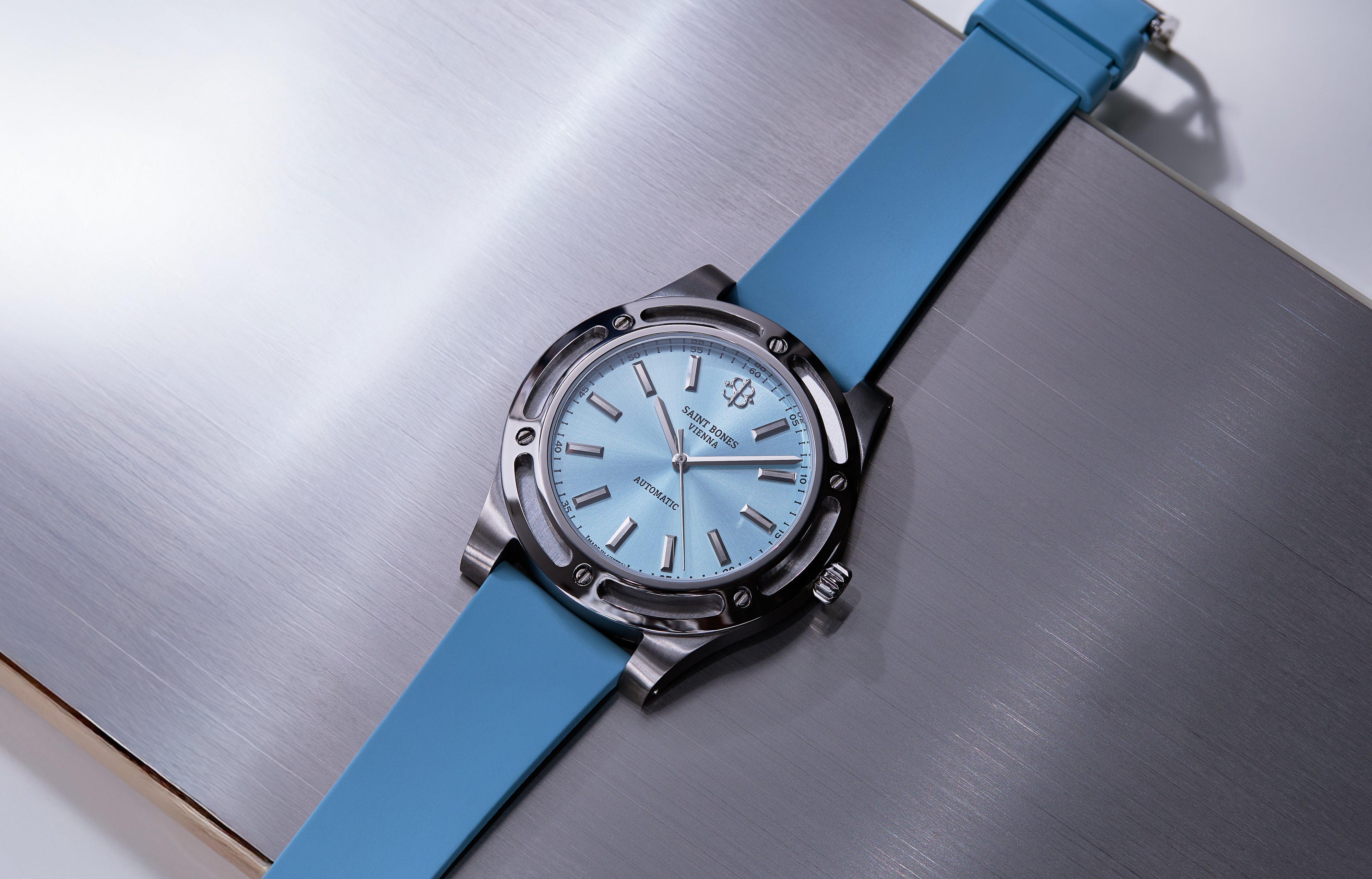 Watch with blue strap and light blue dial on a metallic surface